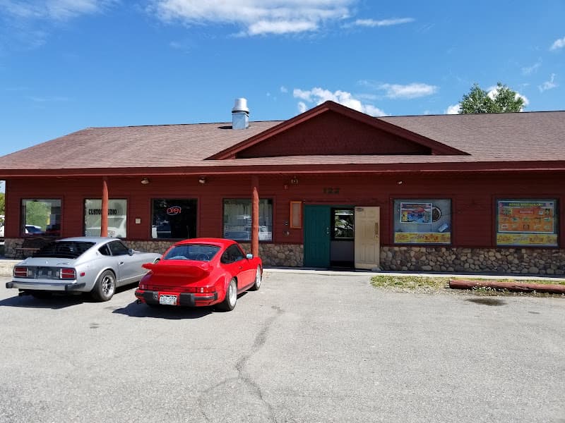 Red wood-sided storefront with teal door and stone base at Custom Audio Design in Silverthorne, Colorado