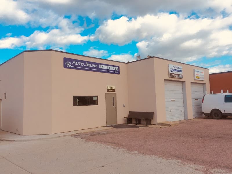 Beige stucco building with a navy sign and two garage doors at Autosound Solutions Inc in South Sioux City, Nebraska
