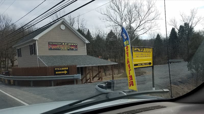 Beige building with yellow signs and a feather flag at On The Go Audio in Birdsboro, Pennsylvania
