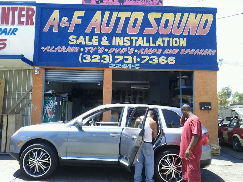 Silver SUV with large wheels and two men beside it at A & F Auto Sounds in Los Angeles, California