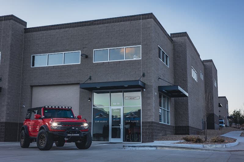Gray block building with red off-road SUV parked out front at Colorado Car Audio in Golden, Colorado