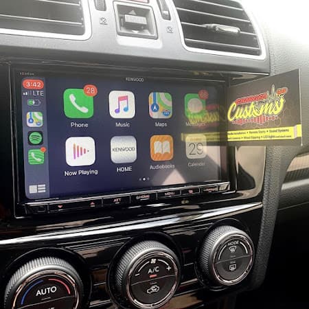 Touchscreen stereo showing CarPlay icons on a car dashboard at Charged Up Customs in Rockville, Maryland