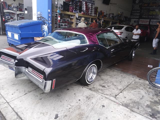 Purple lowrider coupe with white wall tires parked outside a shop at A & A Electronics in Los Angeles, California