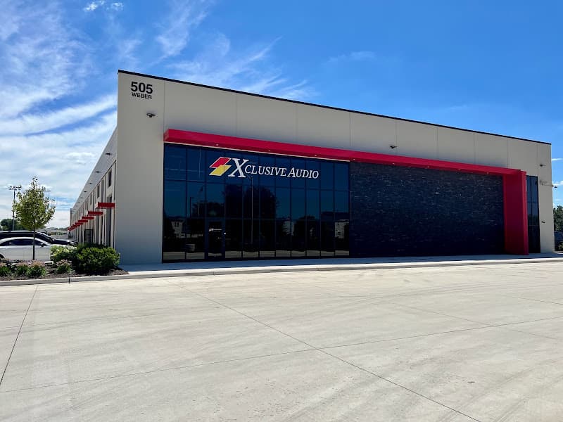 Modern commercial building with red trim and a logo sign at Xclusive Audio LLC in Bolingbrook, Illinois
