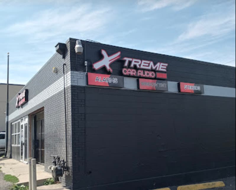 Black brick storefront with signs for alarms and stereos at Xtreme Car Audio in Denver, Colorado