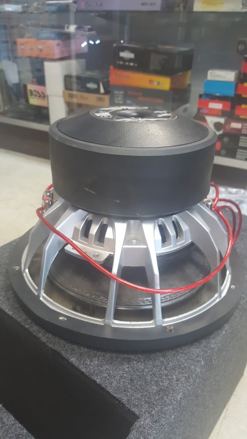 Silver-basket subwoofer with red wires on a gray box at Binny's Electronics in Gary, Indiana
