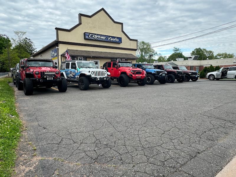 Storefront and row of lifted Jeeps in a parking lot at Extreme Audio & Performance in Manchester, Connecticut