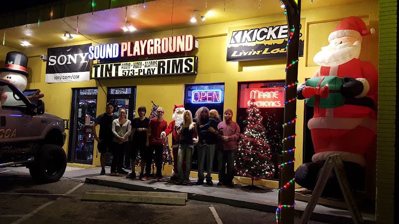 Yellow storefront with inflatable Santa and snowman decorations at Sound Playground Inc. in Cape Coral, Florida