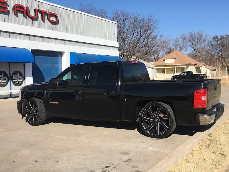 Black pickup truck with large wheels parked outside an auto shop at Street Beats Audio in Wichita, Kansas