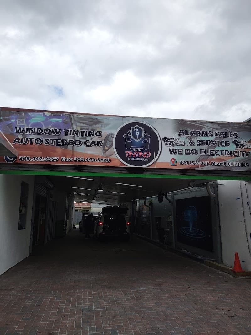 Covered driveway under a sign for window tinting and auto stereo at Audio Tinting & Alarms Inc in Miami, Florida