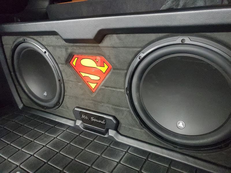 Two subwoofers in a black enclosure with a red and yellow shield logo at Mr. Sound in Aurora, Colorado