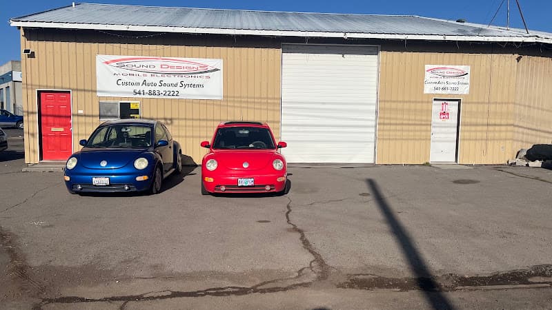 Tan metal building with two parked Volkswagen Beetles at Sound Designs in Klamath Falls, Oregon