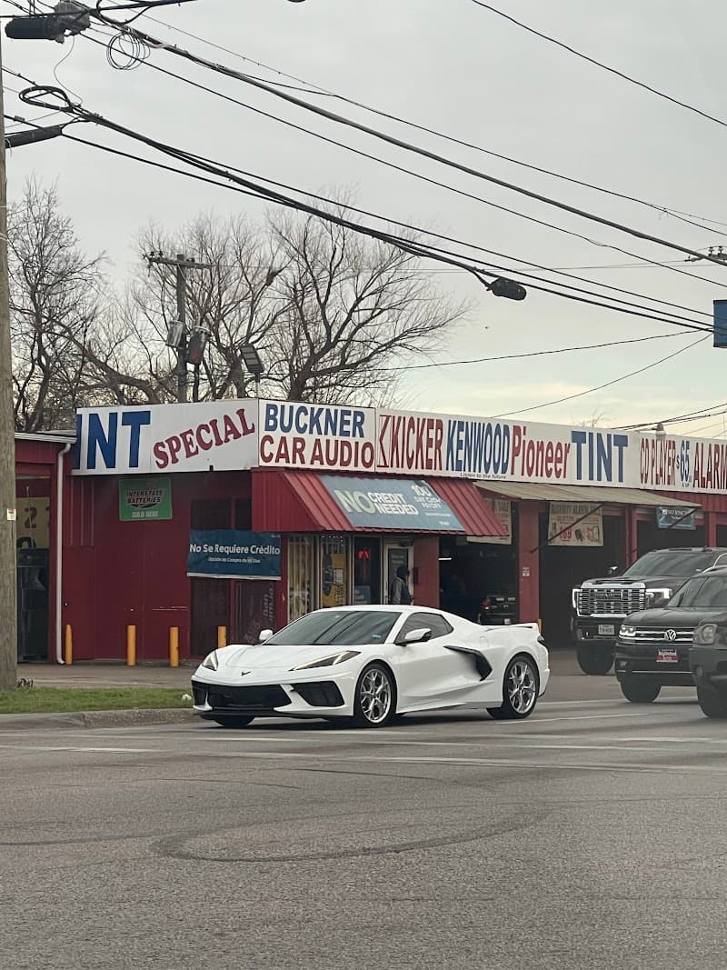 Storefront with red awning and white sports car parked outside at Buckner Car Audio in Dallas, Texas