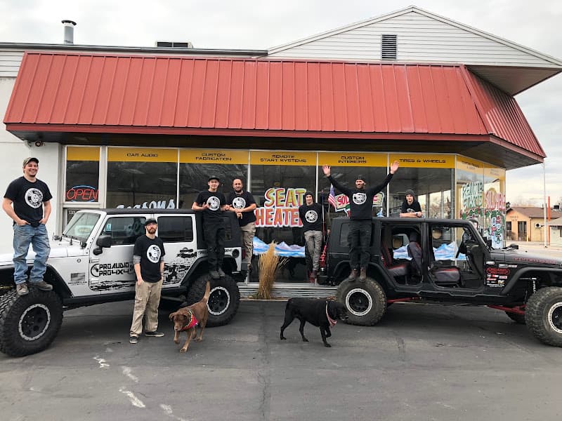 Staff in black shirts posing beside two lifted off-road SUVs at Pro Audio Pro 4x4 in Provo, Utah