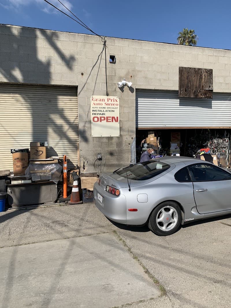 Shop front with open roll-up door and silver coupe parked outside at Gran-Prix Auto Stereo in Culver City, California