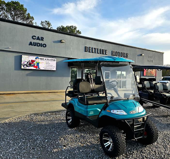 Teal golf cart parked outside gray storefront with Car Audio sign at Beltline Car Audio in Decatur, Alabama