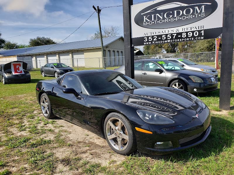 Black sports coupe on a lot beside a dealer sign at Kingdom Motorsports in Groveland, Florida