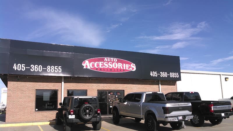 Storefront with black sign, SUV, and two pickup trucks out front at Auto Accessories Unlimited in Norman, Oklahoma