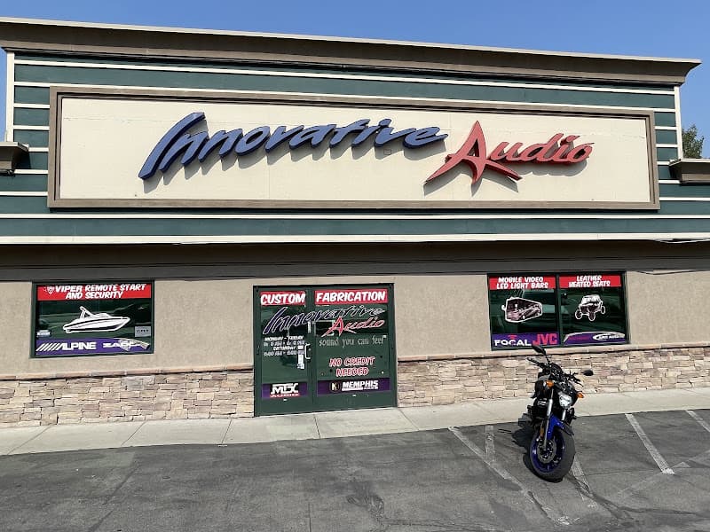 Storefront with large sign, window decals, and motorcycle parked outside at Innovative Audio in Sandy, Utah