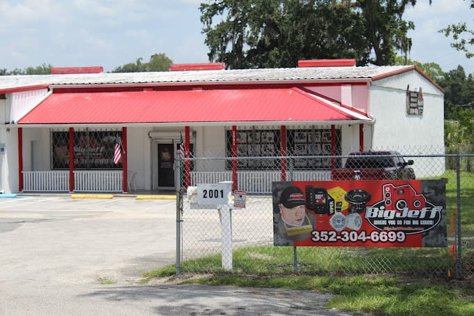 Storefront with red metal roof and banner on fence at Big Jeff Audio in Ocala, Florida
