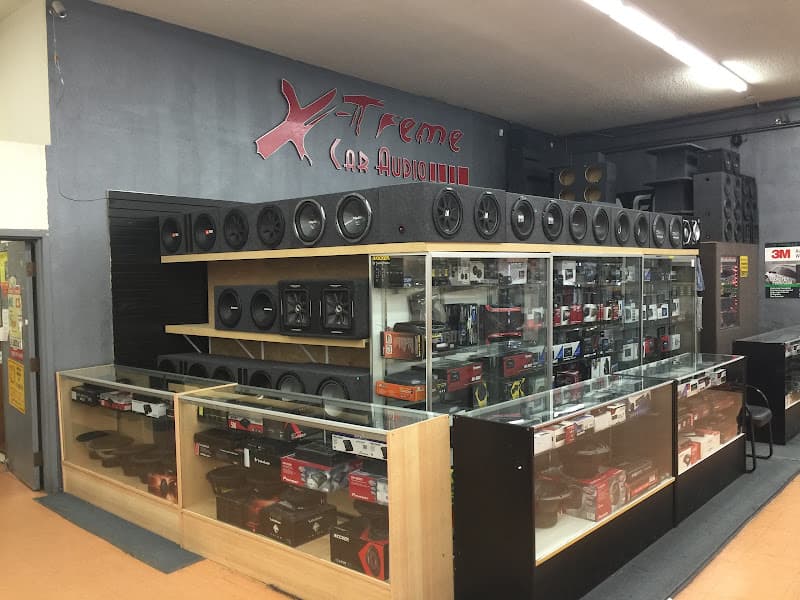 Showroom wall of subwoofers above glass display cases at Xtreme Car Audio in Aurora, Colorado
