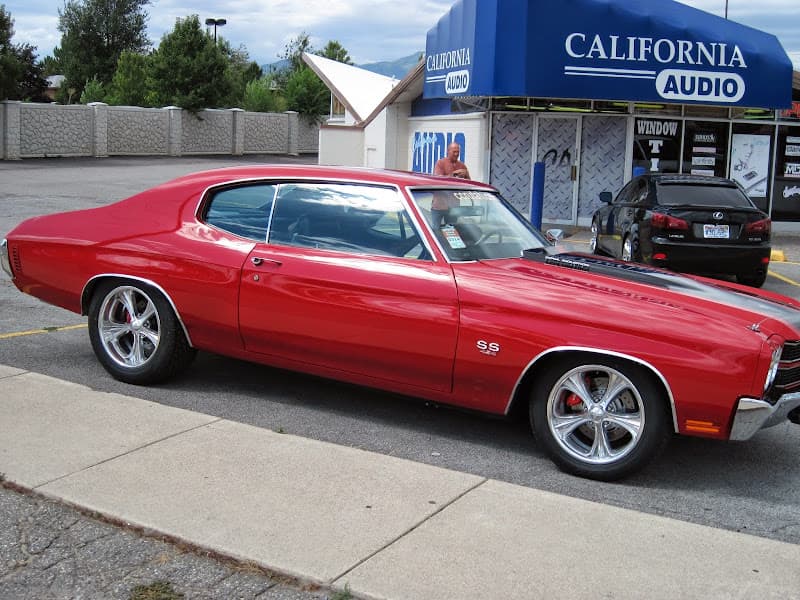 Red classic muscle coupe parked outside a blue awning storefront at California Audio in West Valley City, Utah