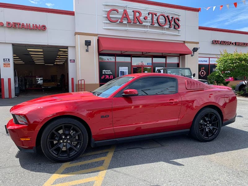 Red sports coupe with black wheels parked outside the storefront at Car Toys in Spokane Valley, Washington