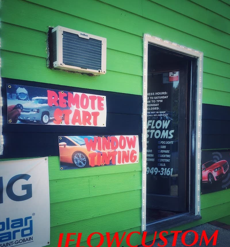 Green storefront with entry door and two vinyl banners at Jflow Custom Carstereo in Mastic, New York