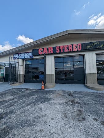 Storefront with two dark bay doors and a red CAR STEREO sign at All Customs Audio in window tint in Brandon, Florida