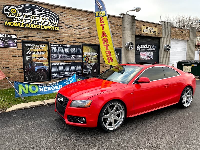 Red Audi coupe with silver wheels parked in front of a brick shop at Music In Motion in Alsip, Illinois