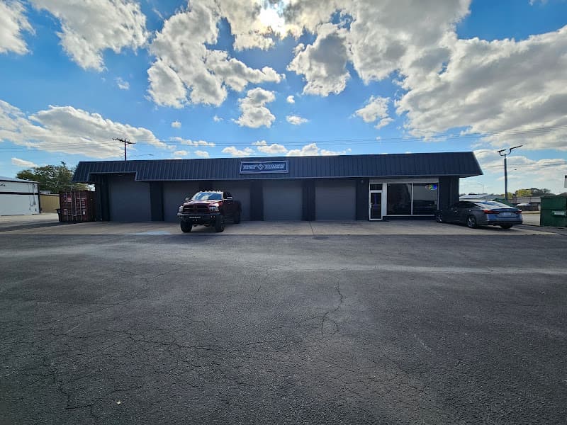 Storefront with four gray roll-up doors and a red pickup outside at Tint and Tunes in Muscle Shoals, Alabama