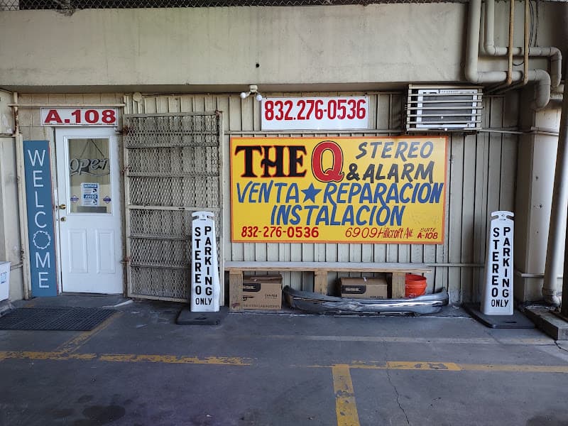 Storefront with yellow sign and white door flanked by parking signs at The Q Stereo and Alarm in Houston, Texas