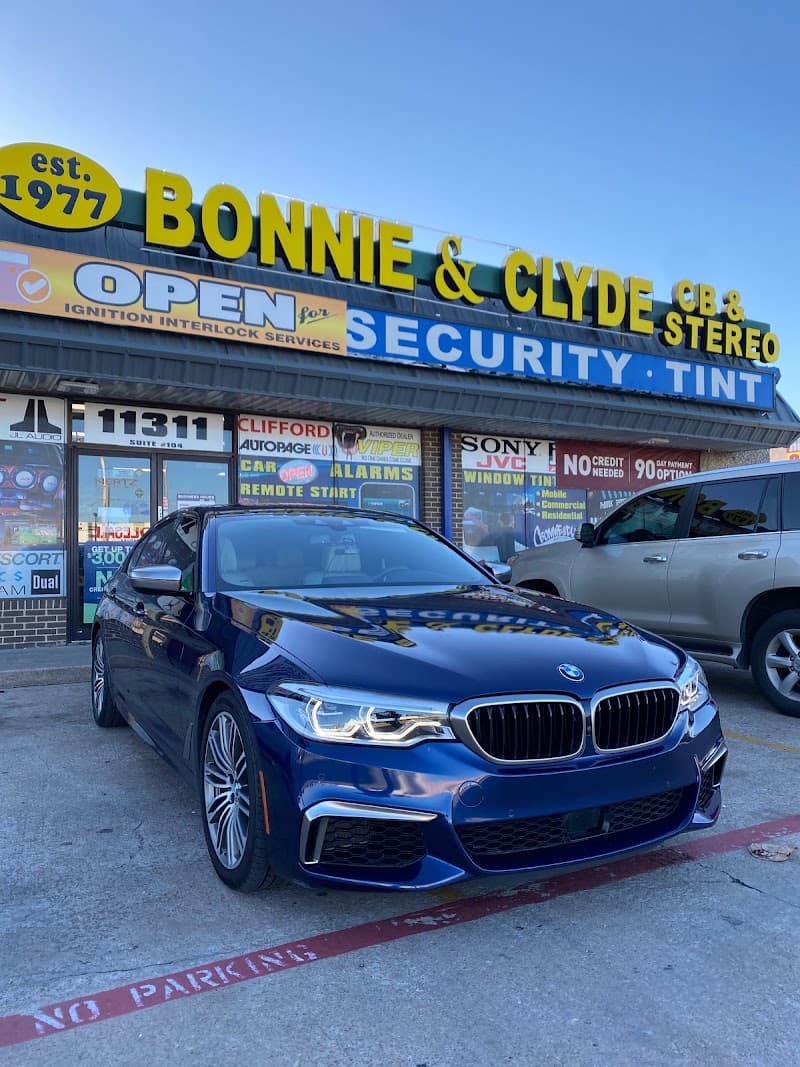 Dark blue BMW sedan parked in front of storefront at Bonnie & Clyde Car Stereo in Dallas, Texas