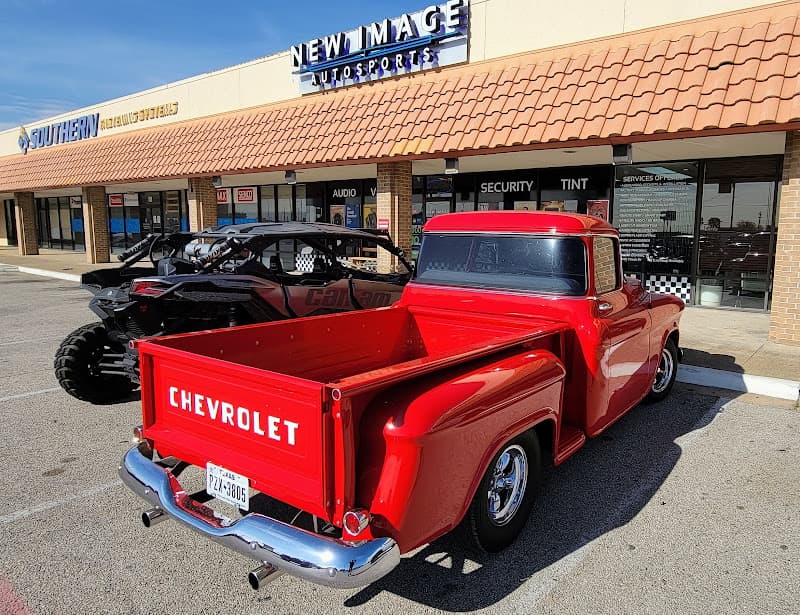 Red Chevrolet pickup truck with chrome bumper parked outside a storefront at New Image Autosports in Garland, Texas