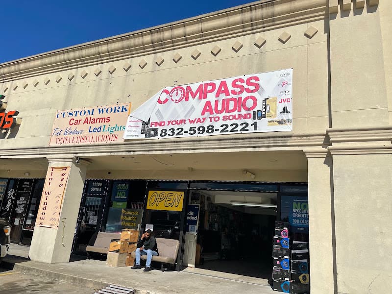 Storefront with a seated man and car alarm signs at High Sound Solution Car audio & Alarms in Houston, Texas