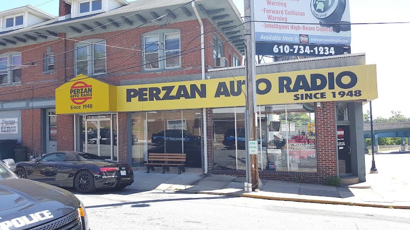 Brick storefront with yellow sign and glass doors at Perzan Auto Radio in Upper Darby Township, Pennsylvania