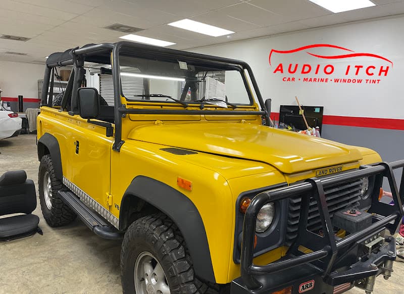 Yellow Land Rover open-top SUV parked in a shop bay at The Audio Itch of Tampa Bay in Tampa, Florida