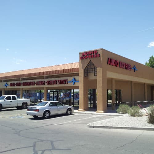 Tan stucco storefront with Audio Express signs and parked cars at Audio Express in Albuquerque, New Mexico