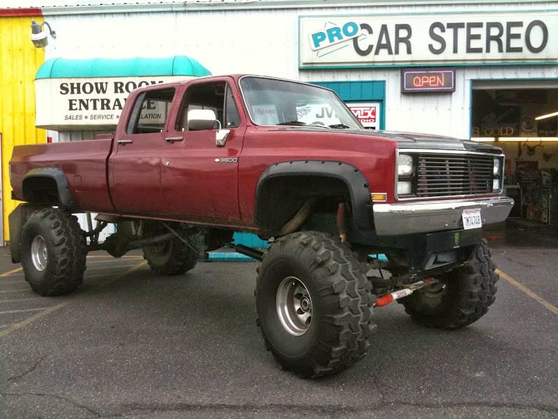 Lifted maroon pickup truck on oversized tires in front of storefront at Pro Car Stereo in Roseburg, Oregon