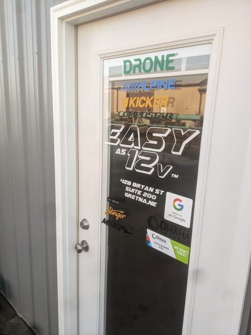 Glass door decorated with Alpine and Kicker brand decals at Easy As 12V in Gretna, Nebraska