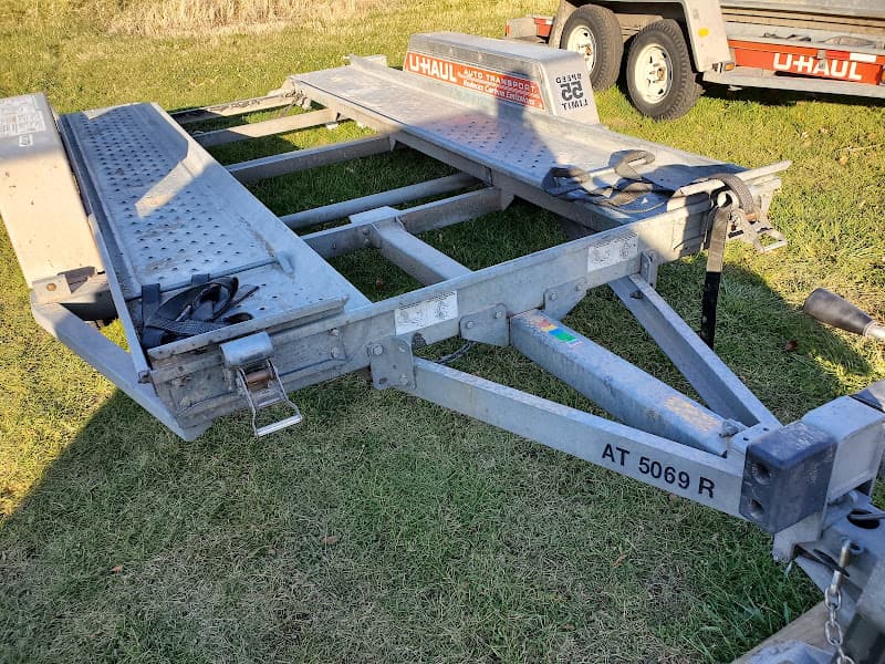 Metal U-Haul auto transport trailer on grass at Tedds Custom Installation & U-Haul in New Lenox, Illinois