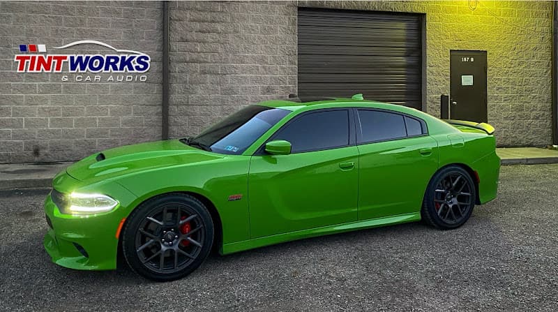 Lime green sedan with dark wheels parked beside a brick building at Tint Works And Car Audio in Columbus, Ohio