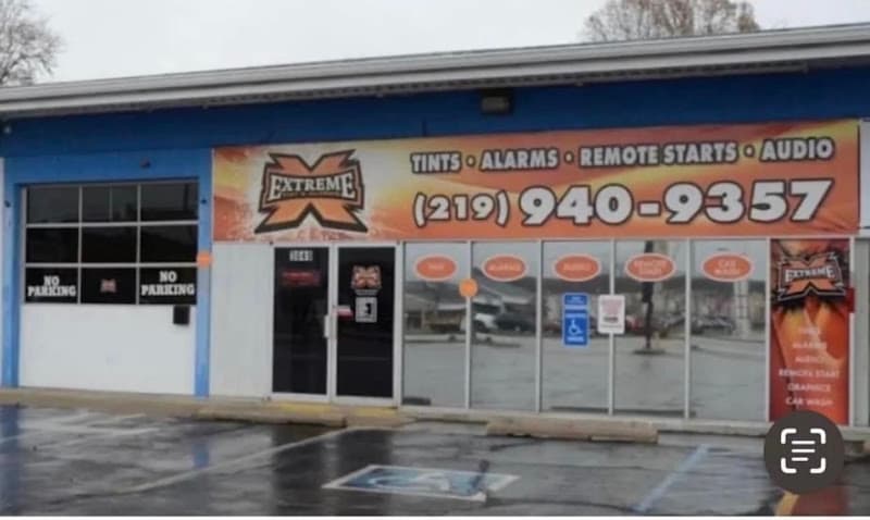Storefront with blue trim and a large orange sign at Extreme Tint & Alarms in Hobart, Indiana