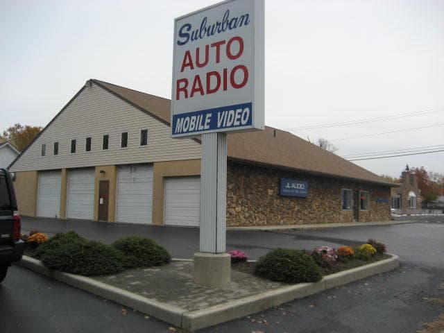 Shop building with a tall pole sign and garage doors at Suburban Auto Radio in Oaklyn, New Jersey