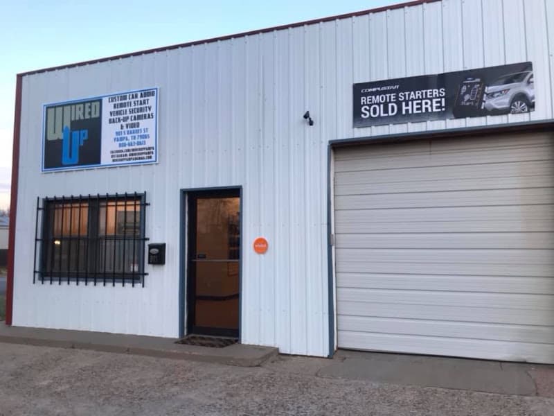 White metal storefront with a roll-up garage door and blue sign at Wired Up in Pampa, Texas