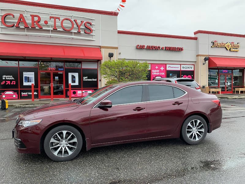 Maroon sedan parked outside storefront with red signs at Car Toys in Rockwall, Texas