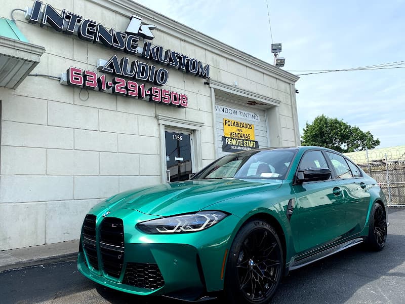 Green sedan parked outside a shop with a window tinting sign at Intense Kustom Audio in Brentwood, New York