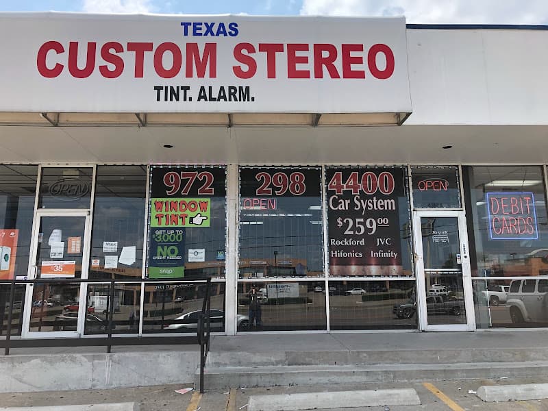 Storefront with window signs and a red and blue store sign at Texas Custom Stereo in Dallas, Texas