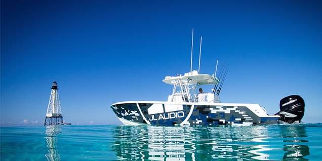 Boat with JL Audio camo wrap on open water near a lighthouse at Auto Sound Cape Coral in Cape Coral, Florida