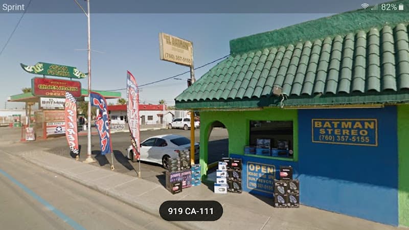 Green-roofed storefront with BATMAN STEREO sign and speaker boxes at El Batman Audio Thority in Calexico, California